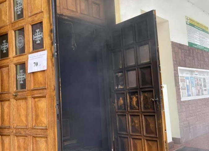 Wejście do kościoła św. Krzyża w Lublinie, ze środka wydobywa się dym.