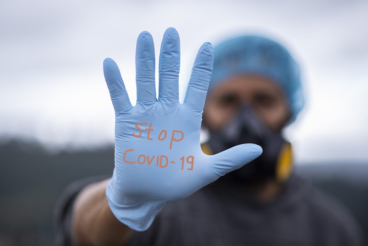 Człowiek pokazuje rękawiczkę z napisem "STOP COVID"