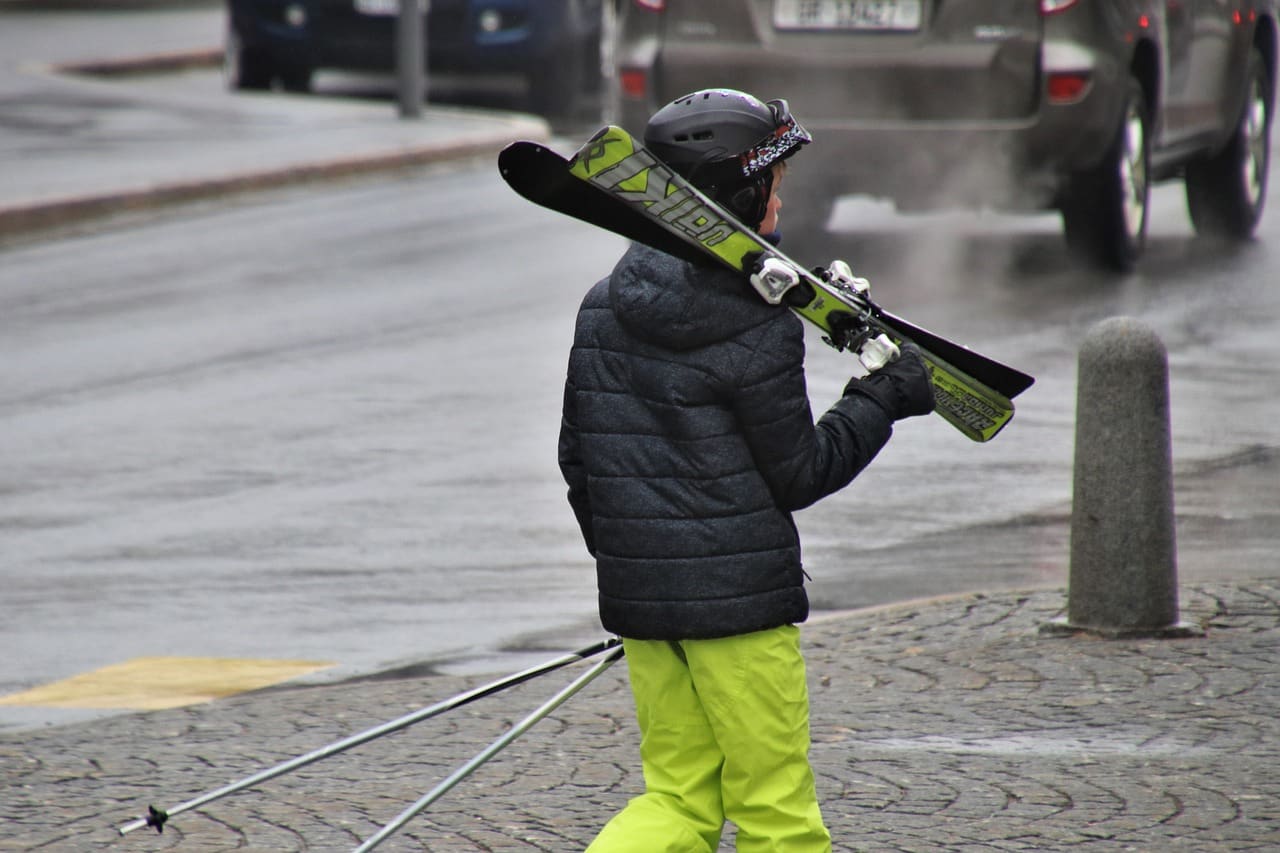 Mały narciarz idzie ulicą.