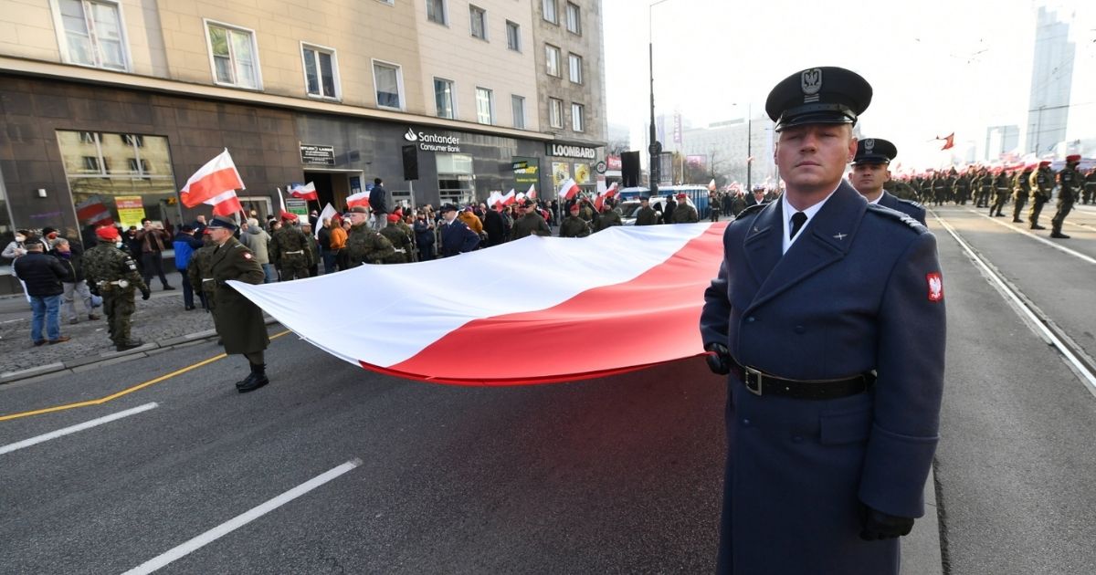 Uczestnicy Marszu Niepodległości niosą gigantyczną flagę Polski.
