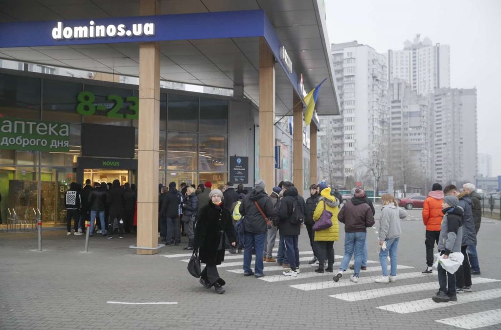 Ludzie stoją w kolejce przed sklepem spożywczym w Kijowie.