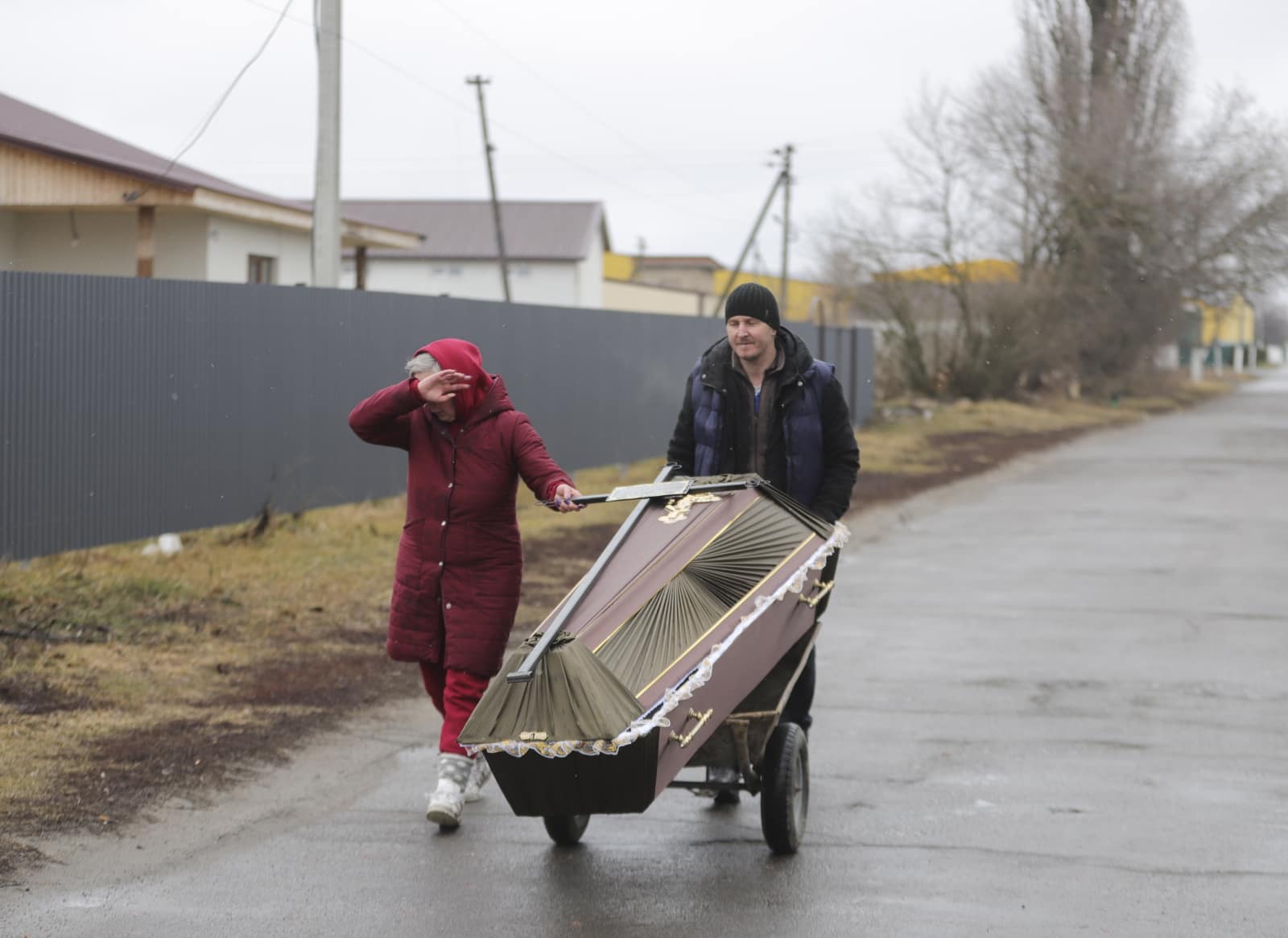 Mieszkańcy przenoszą trumnę po ostrzale miasta w Borodziance koło Kijowa